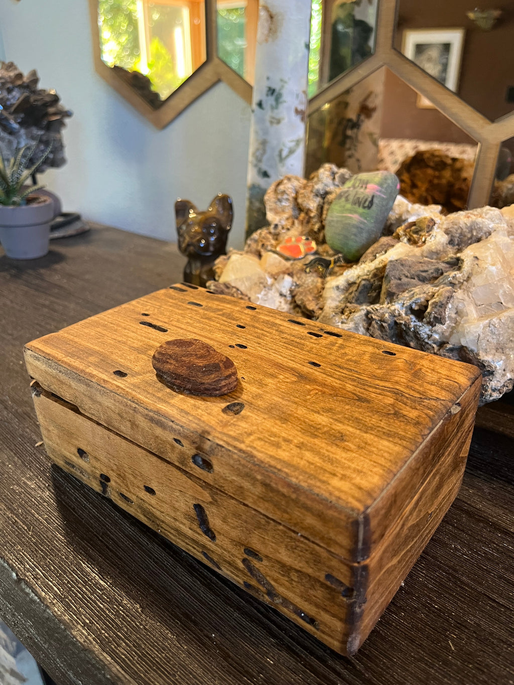A rustic keepsake box made from Ash wood with a Oregon coast beach wood handle and lots of bug damage details, displayed on a dark wooden table in a styled home decor setting.