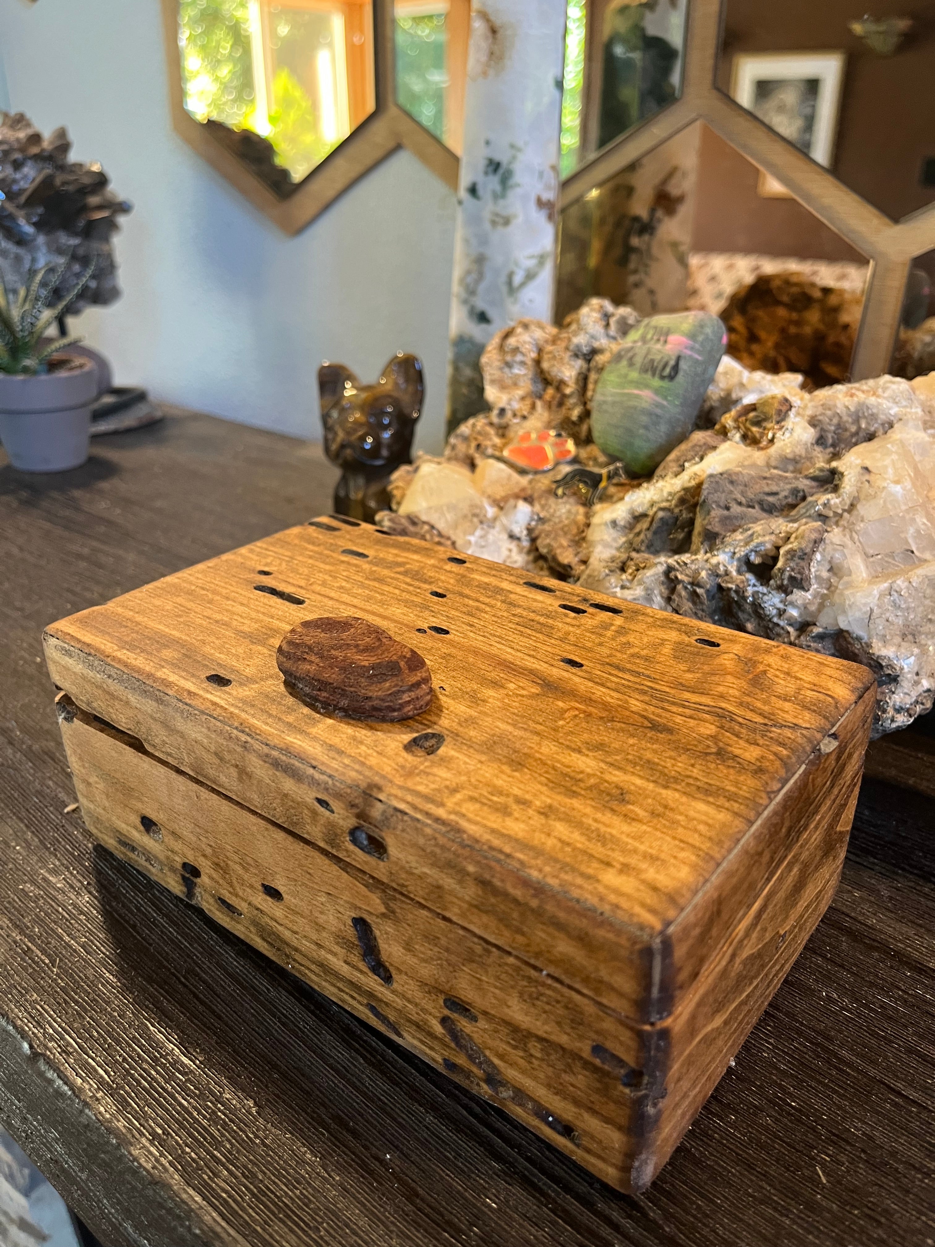 A rustic keepsake box made from Ash wood with a Oregon coast beach wood handle and lots of bug damage details, displayed on a dark wooden table in a styled home decor setting.